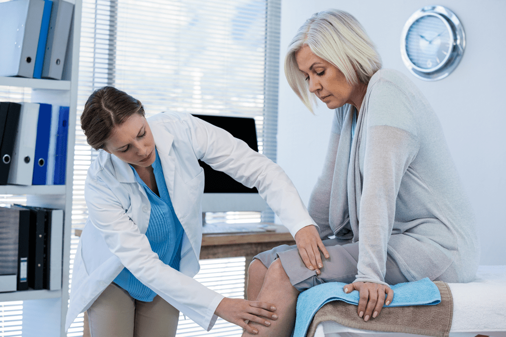The doctor examines the patient with osteoarthritis of the knee joint